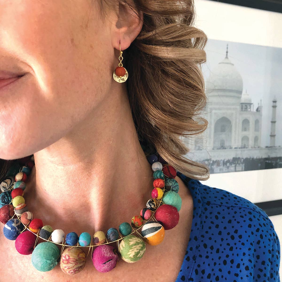 Kvinna som bär Kantha Camille-örhängen och pärlhalsband