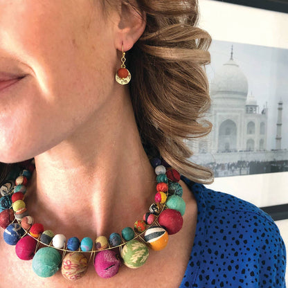 Kvinna som bär Kantha Camille-örhängen och pärlhalsband