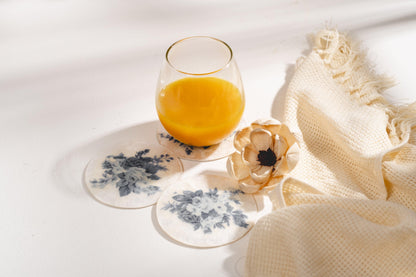 Capiz-underlägg med blå blommor under ett glas apelsinjuice