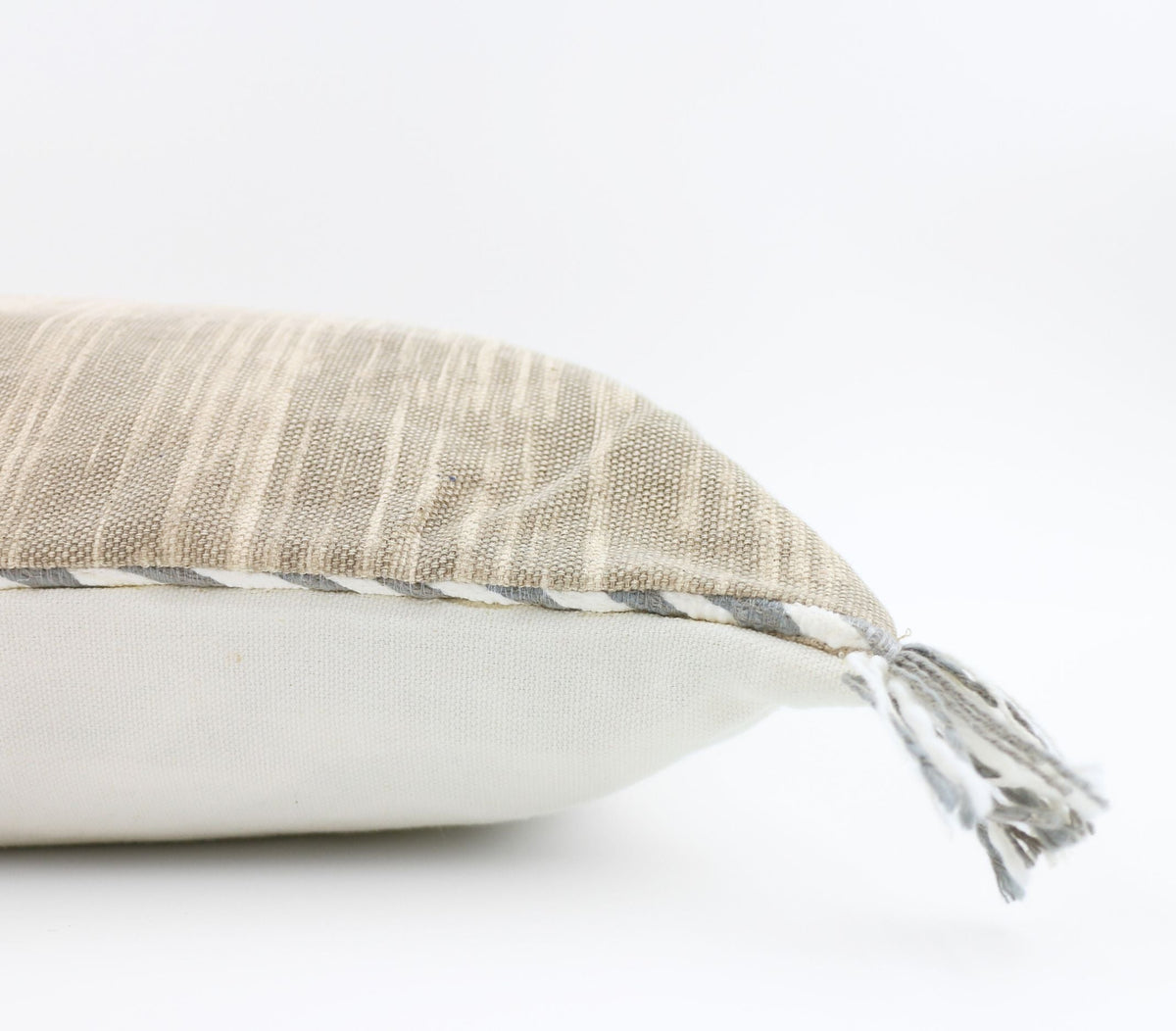 Minimalistinen beige tyyny sivulta kulmatupsuineen