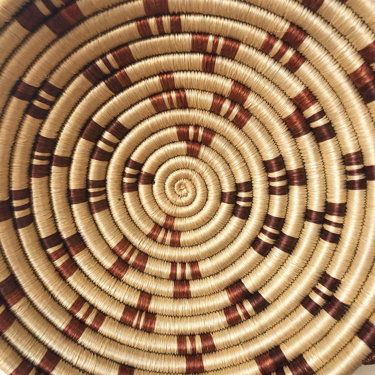 Närbild av Cyarwa-skålens spiralflätning med bruna motiv